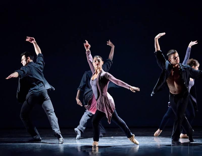 Group of male and female contemporary student dancers on stage with dramatic lighting